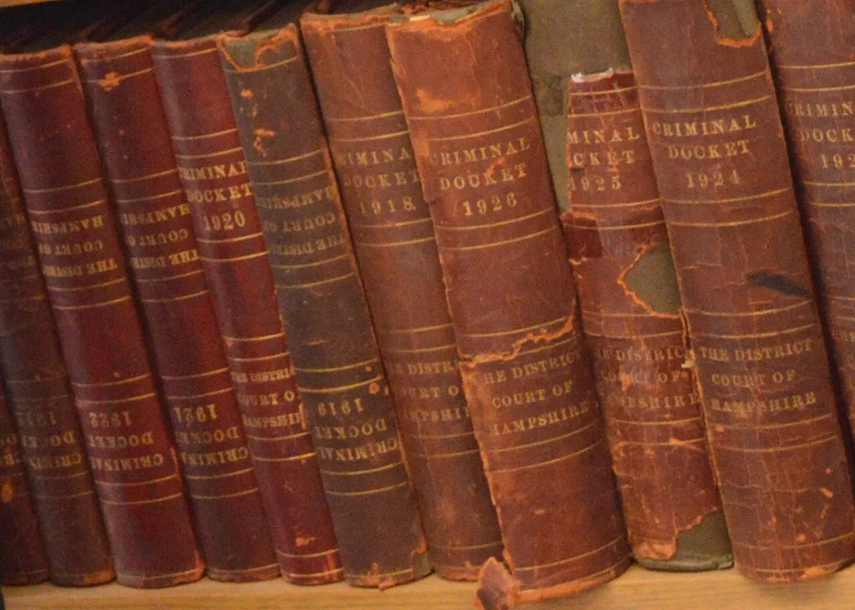 Rij oude, versleten wetboeken met verguld opschrift op een boekenplank