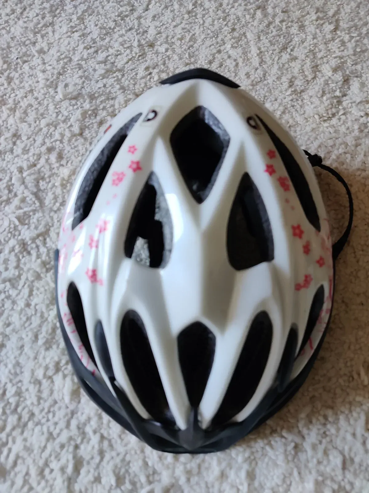 Witte fietshelm met roze sterretjesprint, bovenaanzicht met ventilatiegaten